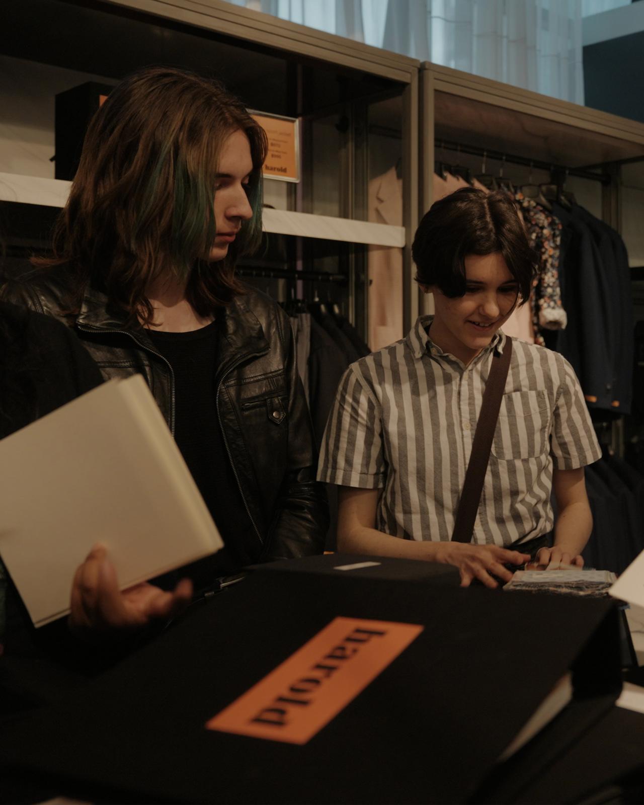 two people are looking at a fabric book at Harry Rosen