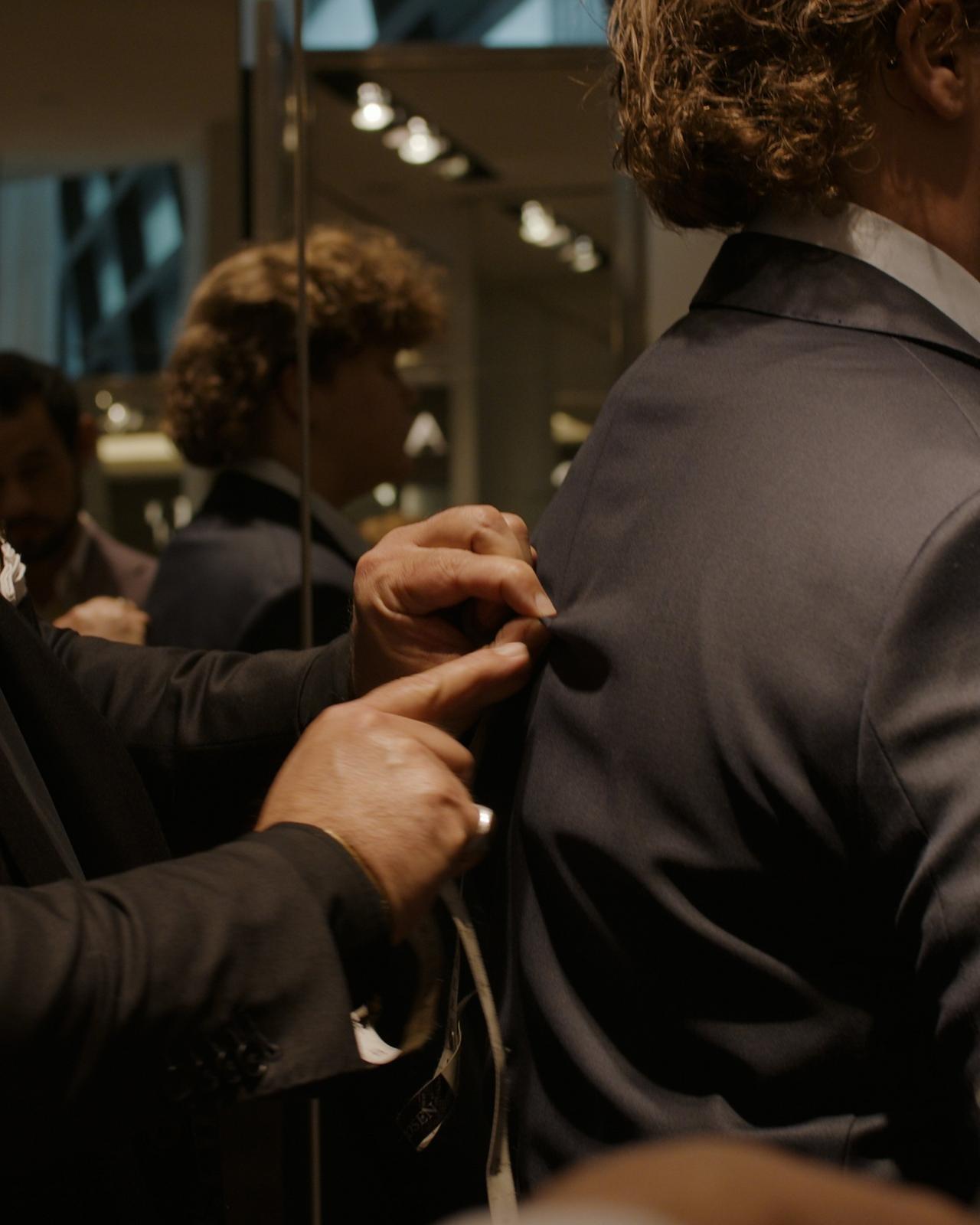 a man in a suit adjusting his tie in a mirror