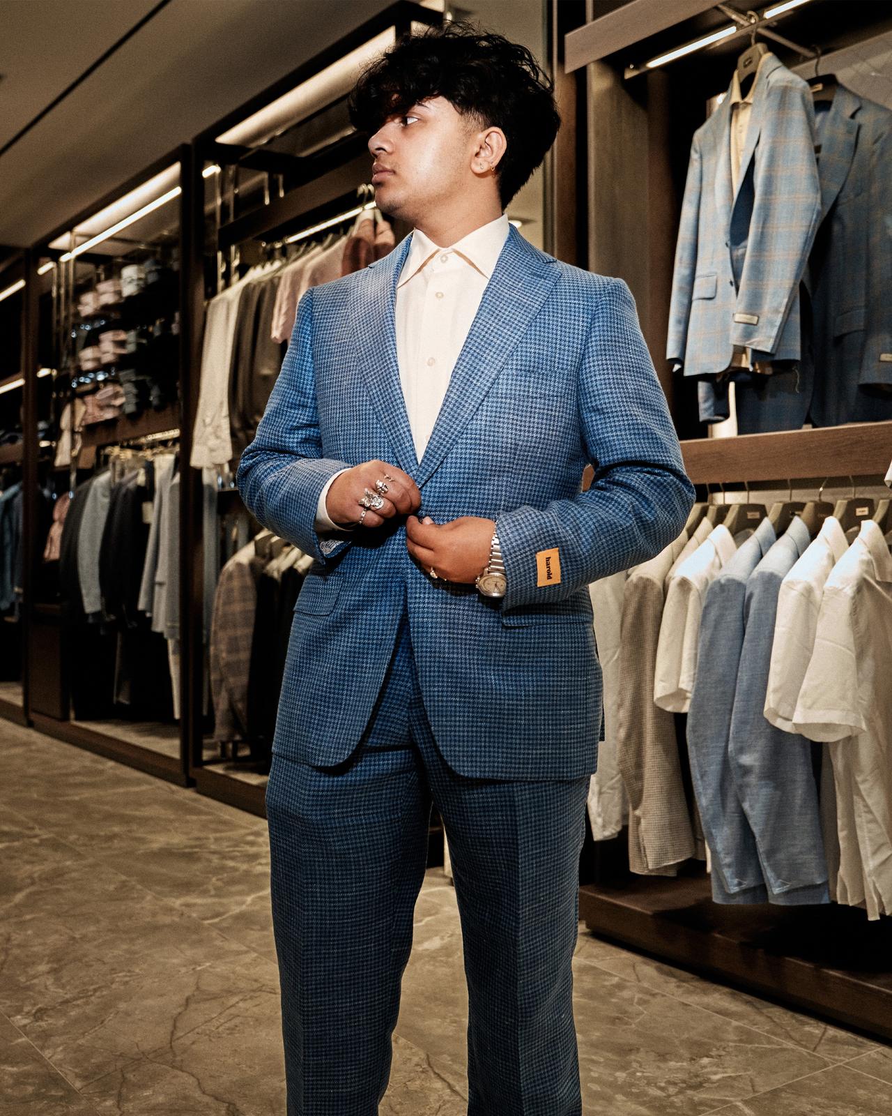 a person in a suit standing in front of a rack of clothes