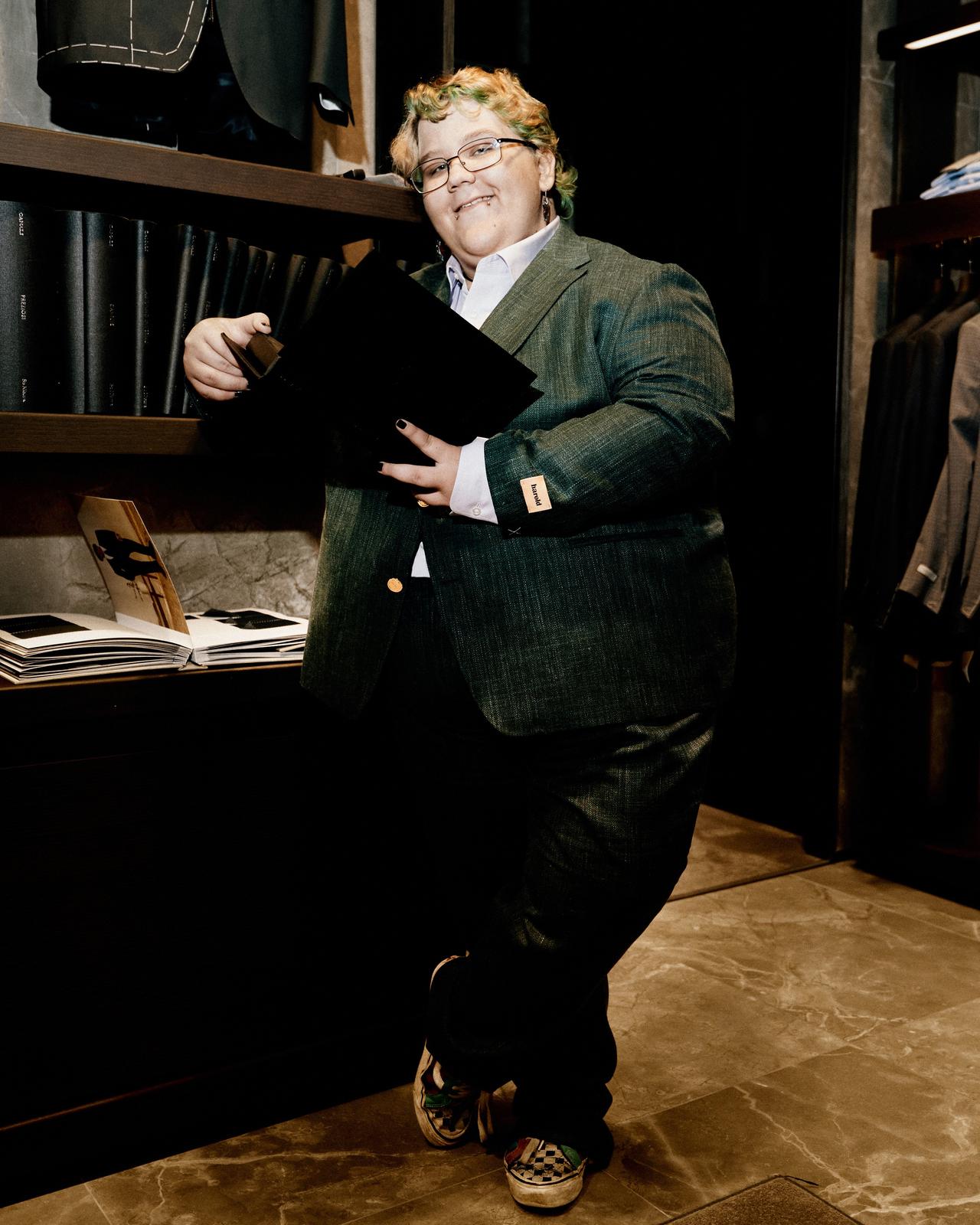 a person in a suit standing in front of a rack of clothes