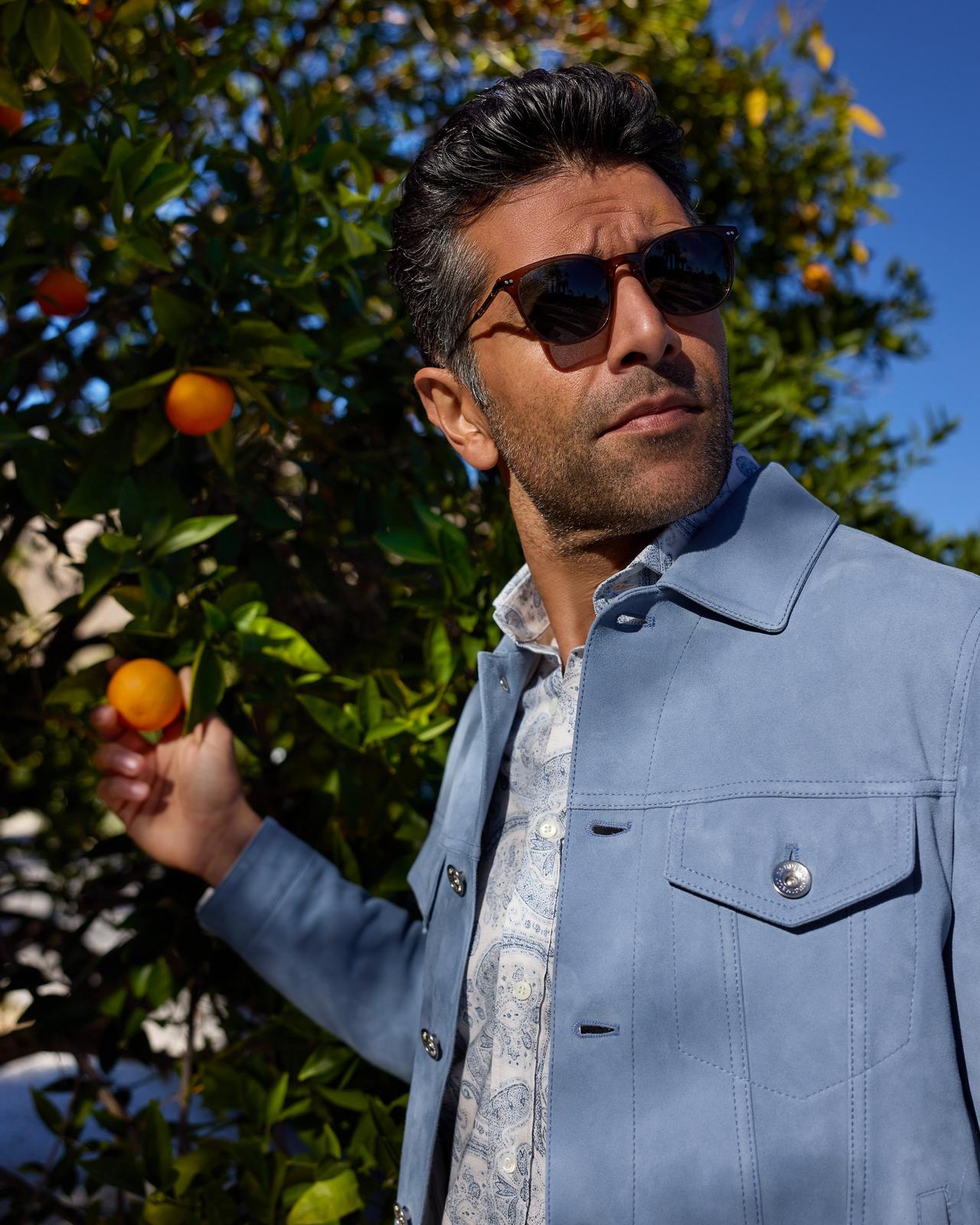 a man in a blue jacket holding an orange in his hand