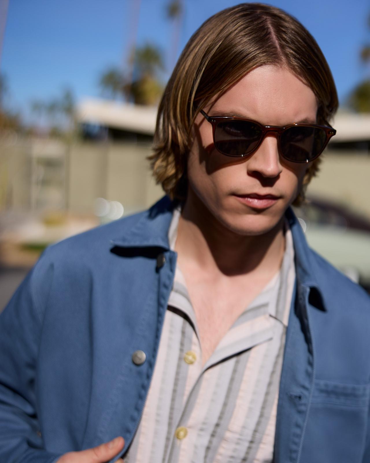 a close up of a man in sunglasses and a blue jacket