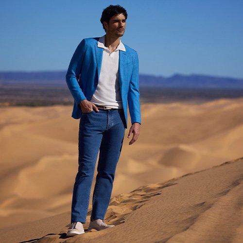 A man in a blue jacket standing on a desert