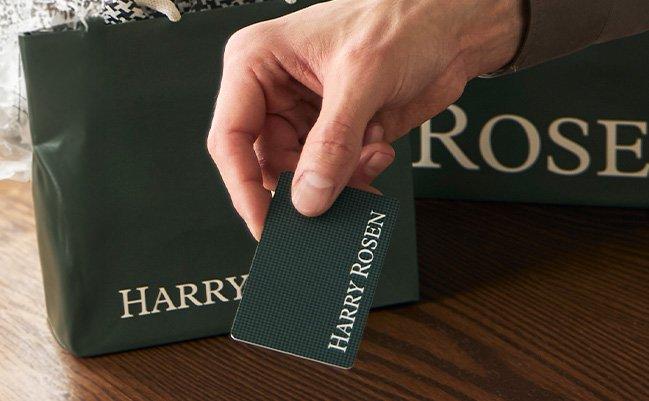 male hand holding harry rosen gift card over counter