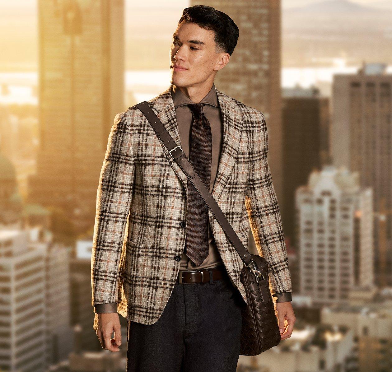 A model in a suit and tie standing in front of a cityscape