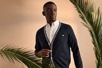 Image 13: A man wearing a dark blue lightweight sweater and knit layered over a white shirt