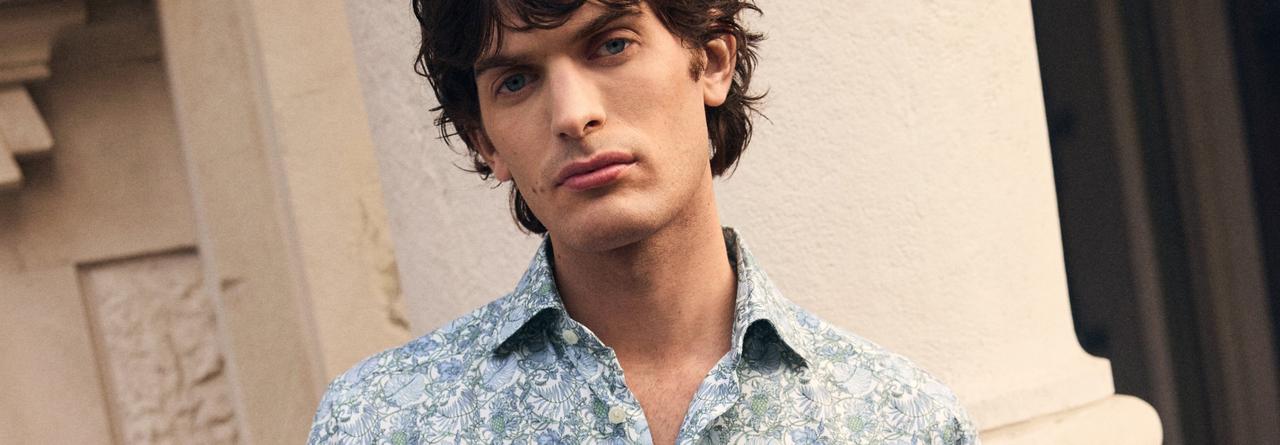 A man wearing a light blue floral pattern design shirt