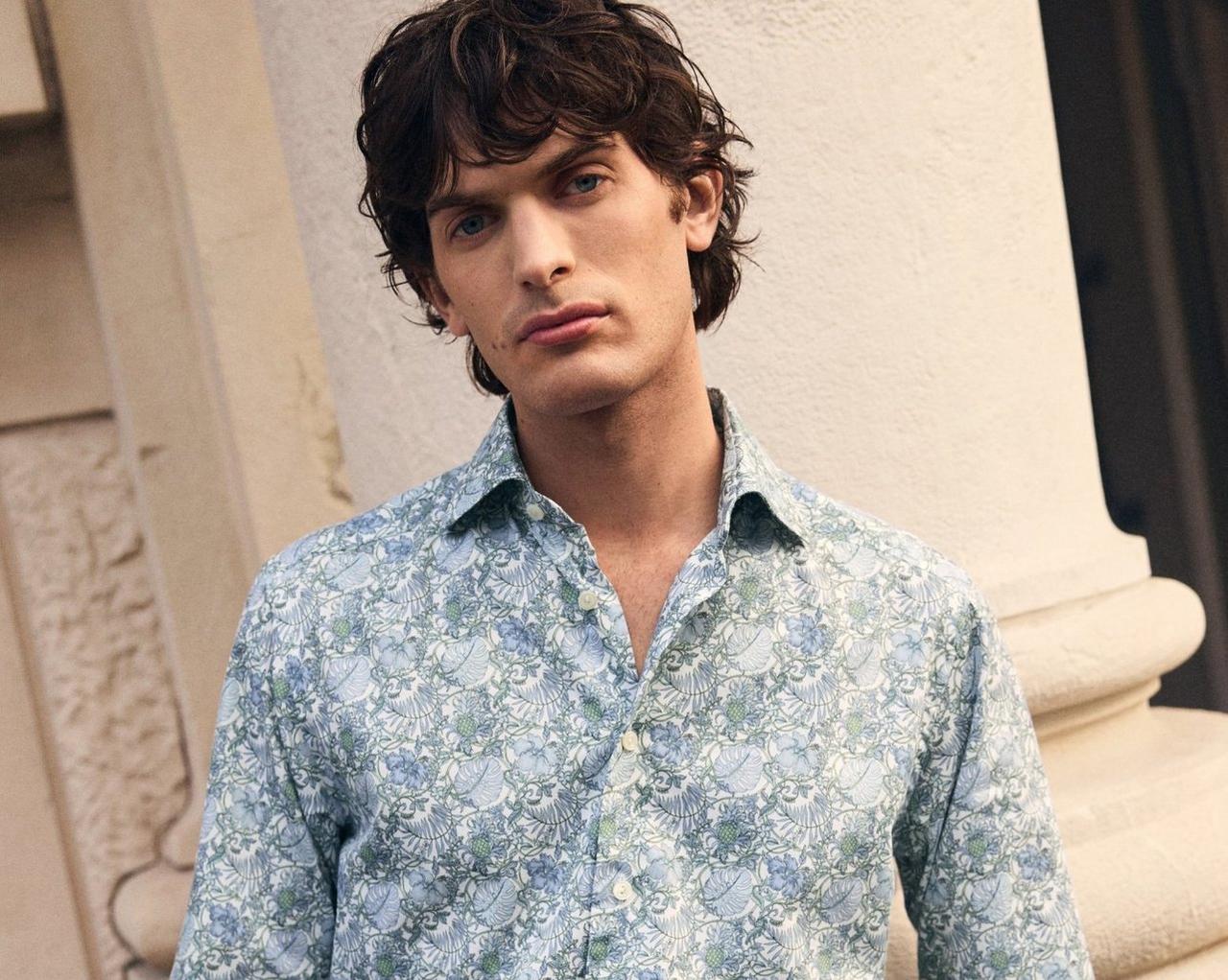 A man wearing a light blue floral pattern design shirt