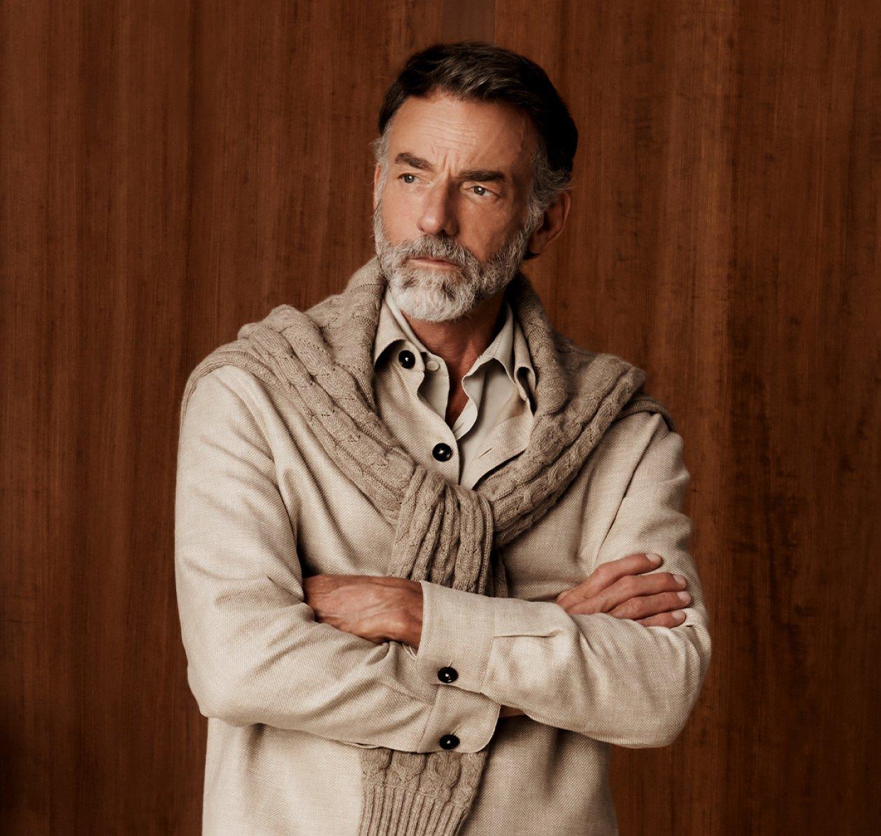 Un homme portant une chemise beige avec un chandail moka pâle