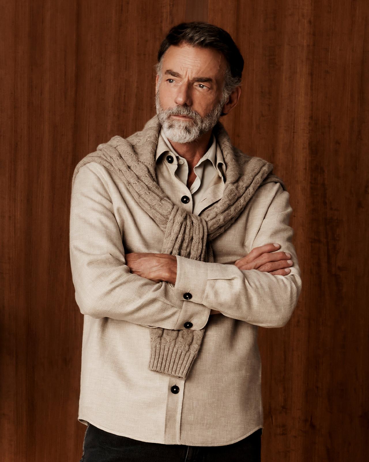 A man wearing a soft beige shirt with beige brown sweater and black pants