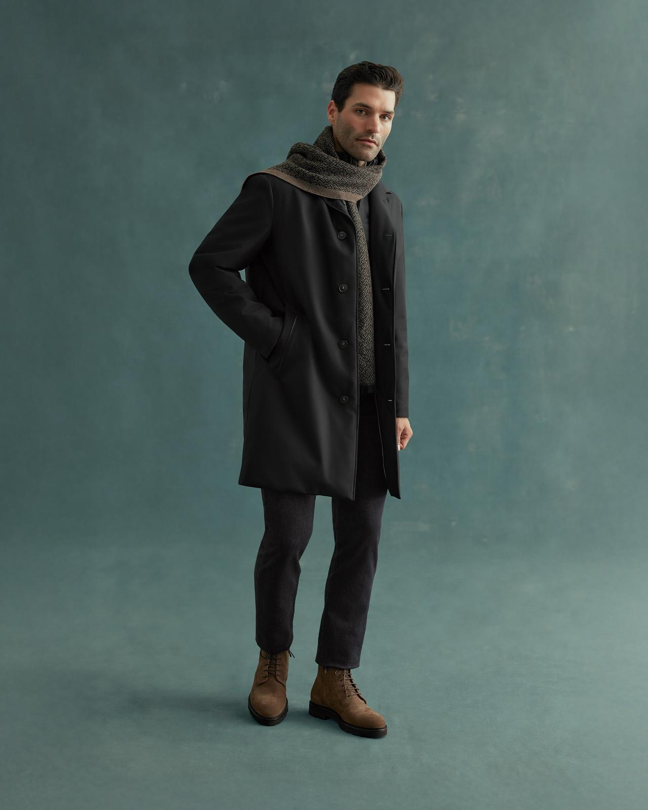 Man wearing a black Canali coat and pants with a scarf, paired with brown boots