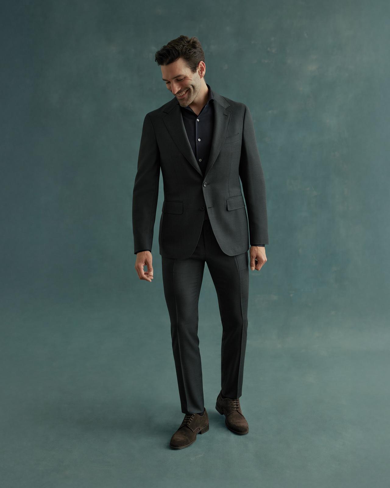 Man wearing a black Canali blazer over a black shirt and black pants, paired with black dress shoes