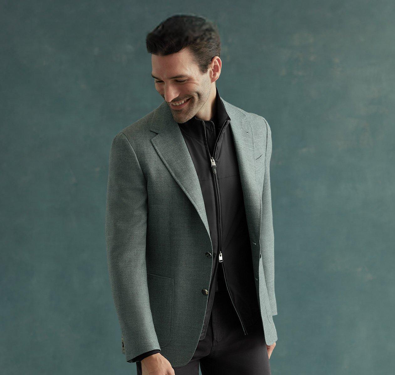 Un homme portant un veston vert Canali sur une chemise noire et un pantalon noir avec des chaussures habillées noires