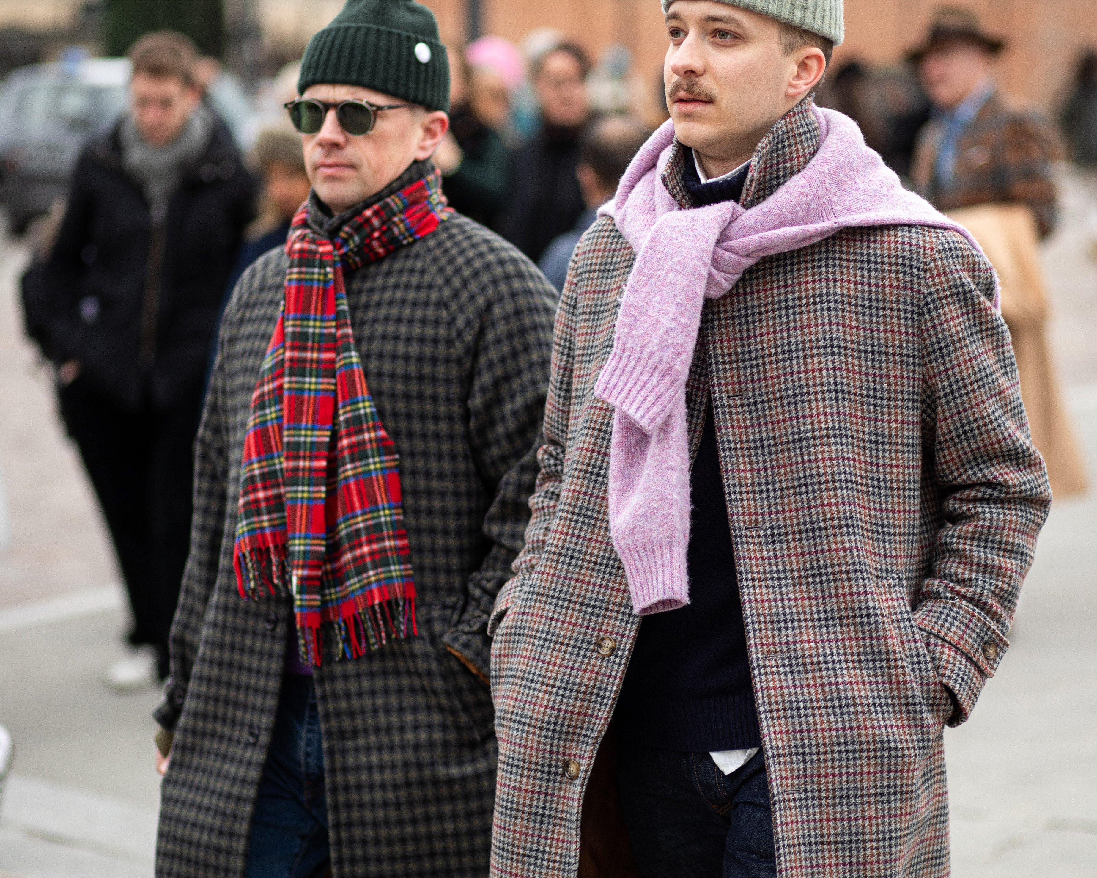 Two men walking down a city street wearing coats and scarves