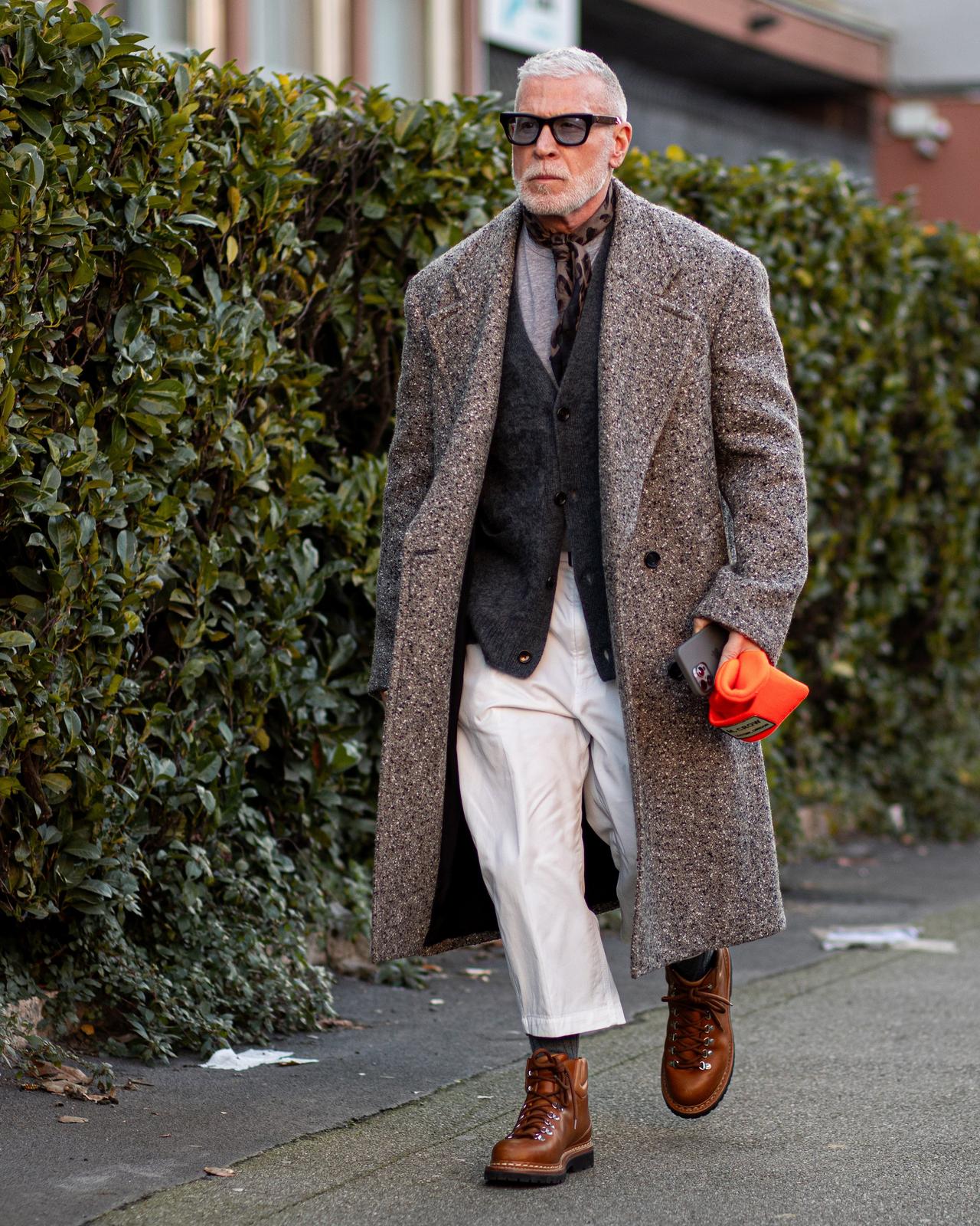 A man in a coat and tie walking down a sidewalk