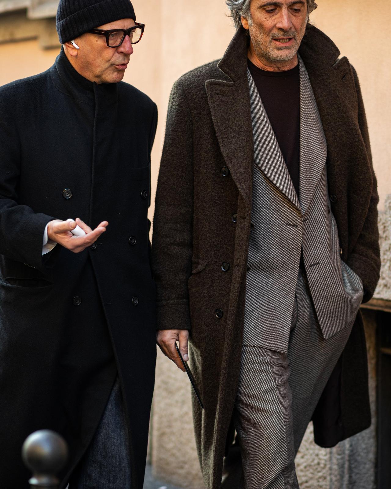 Two men walking down a street talking on cell phones