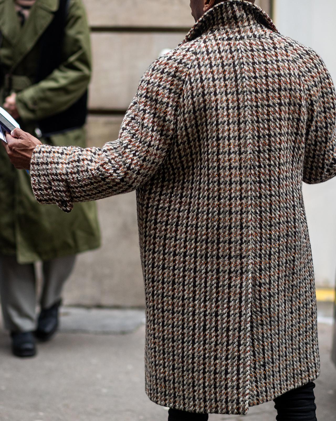 Un homme en manteau et chapeau marchant dans une rue