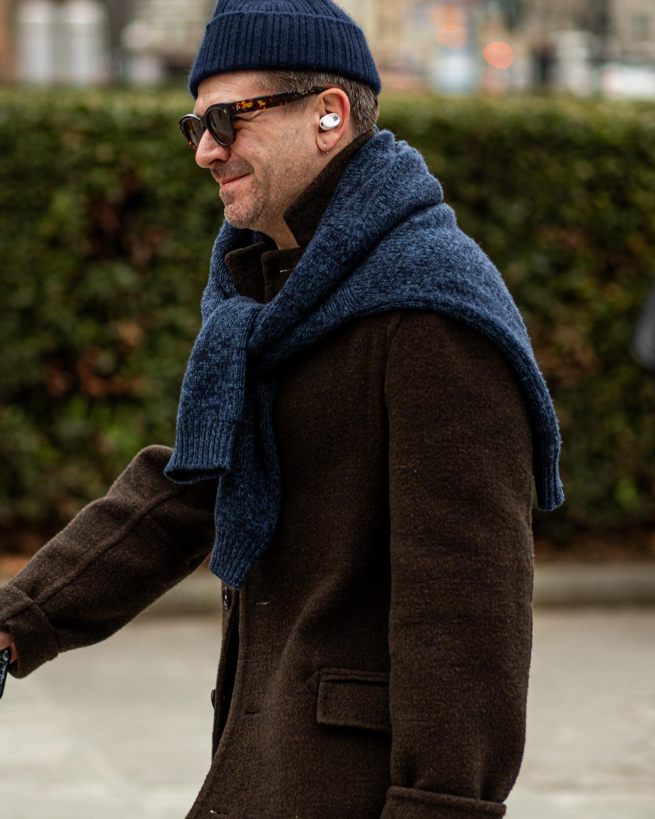 Un homme vêtu d'une veste bleue et d'un foulard marchant dans la rue