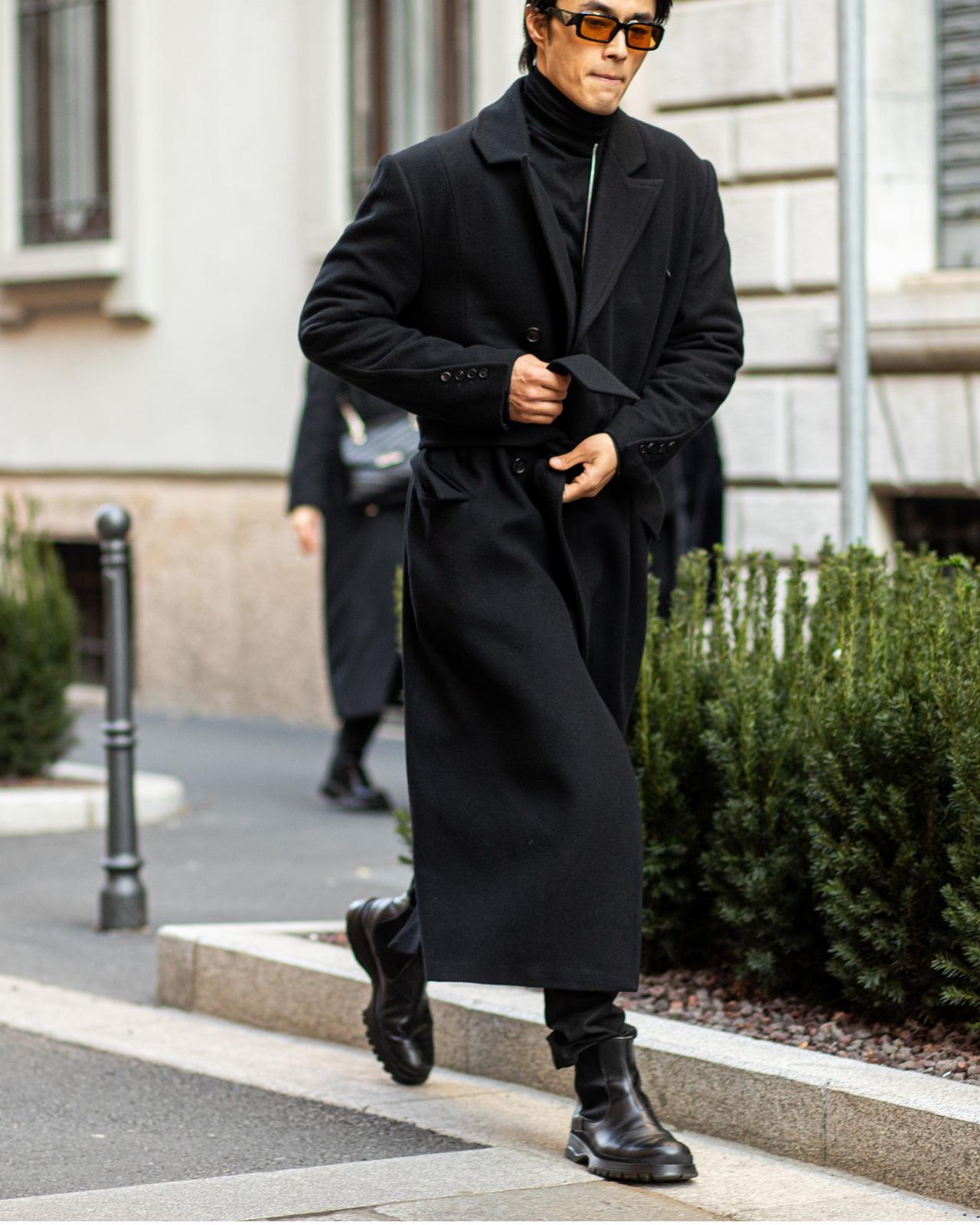 Un homme en manteau noir marchant dans une rue