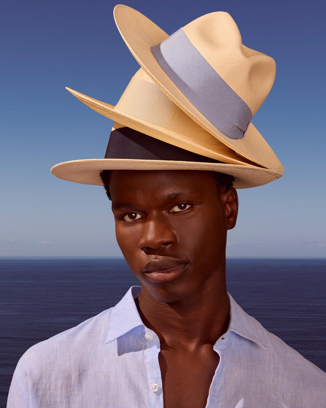 A man with three hats on his head, one on top of the other.