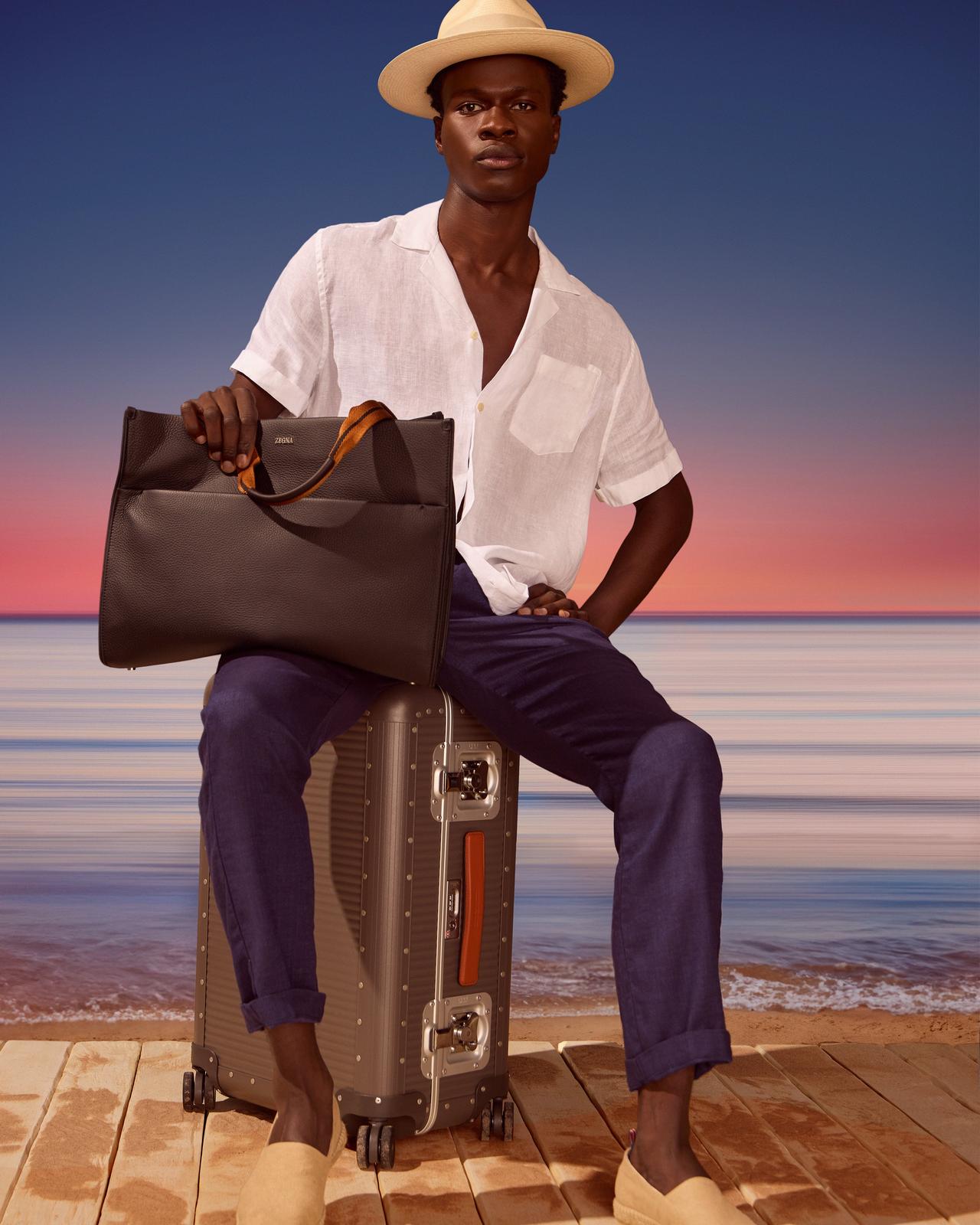 A man sitting on a suitcase with a briefcase in his hand.