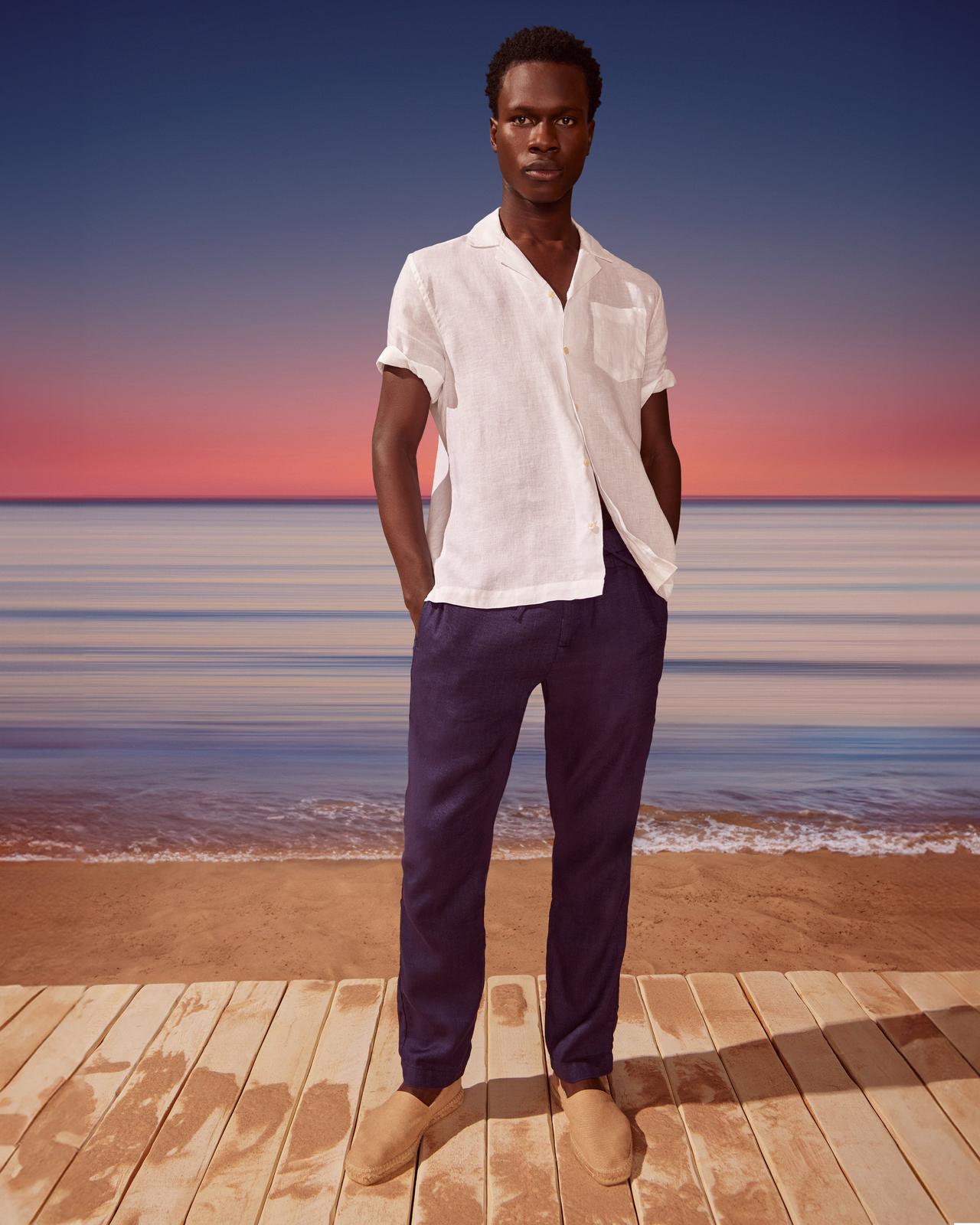 A man standing on a wooden deck near the ocean.