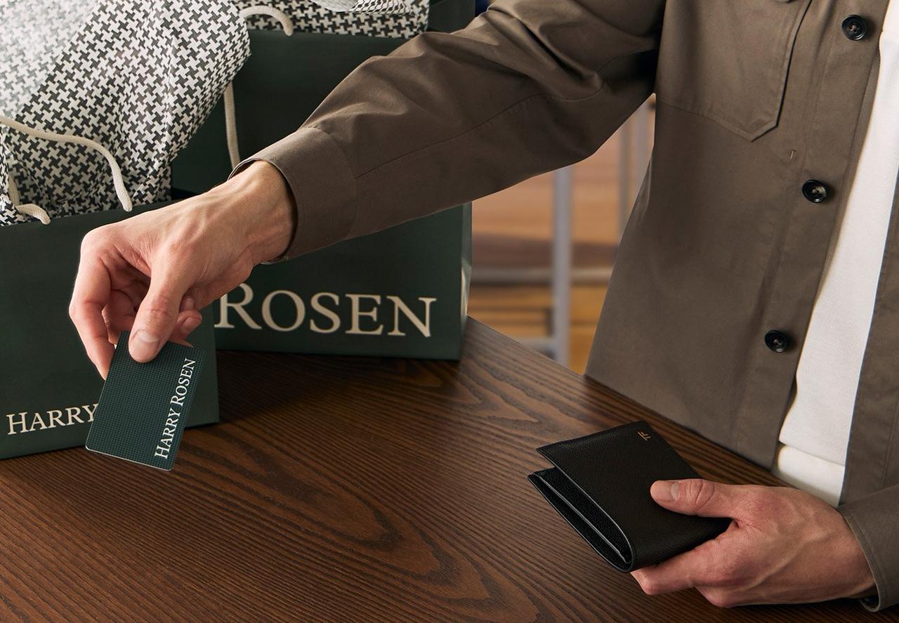 male hands holding gift card and wallet over harry rosen cash desk