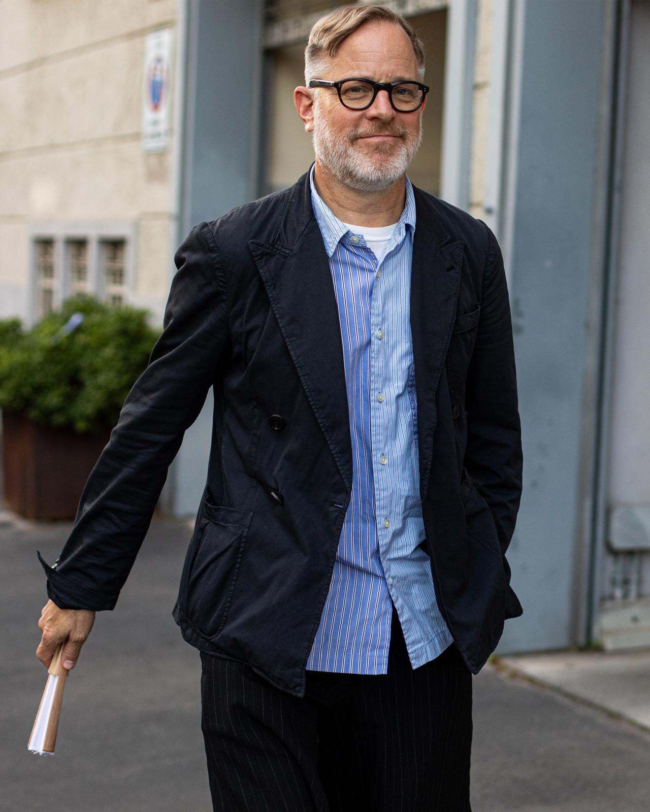 homme portant des lunettes marchant dehors portant une chemise de sport, une veste de sport et un pantalon habillé