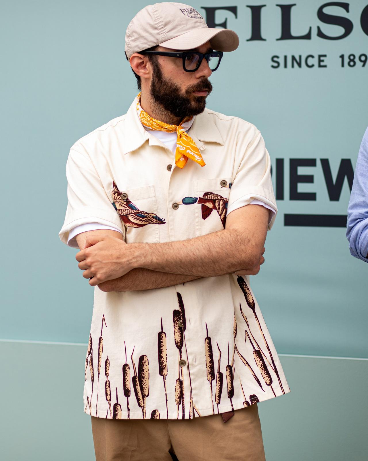 a man with a hat and glasses standing next to a man with a tie