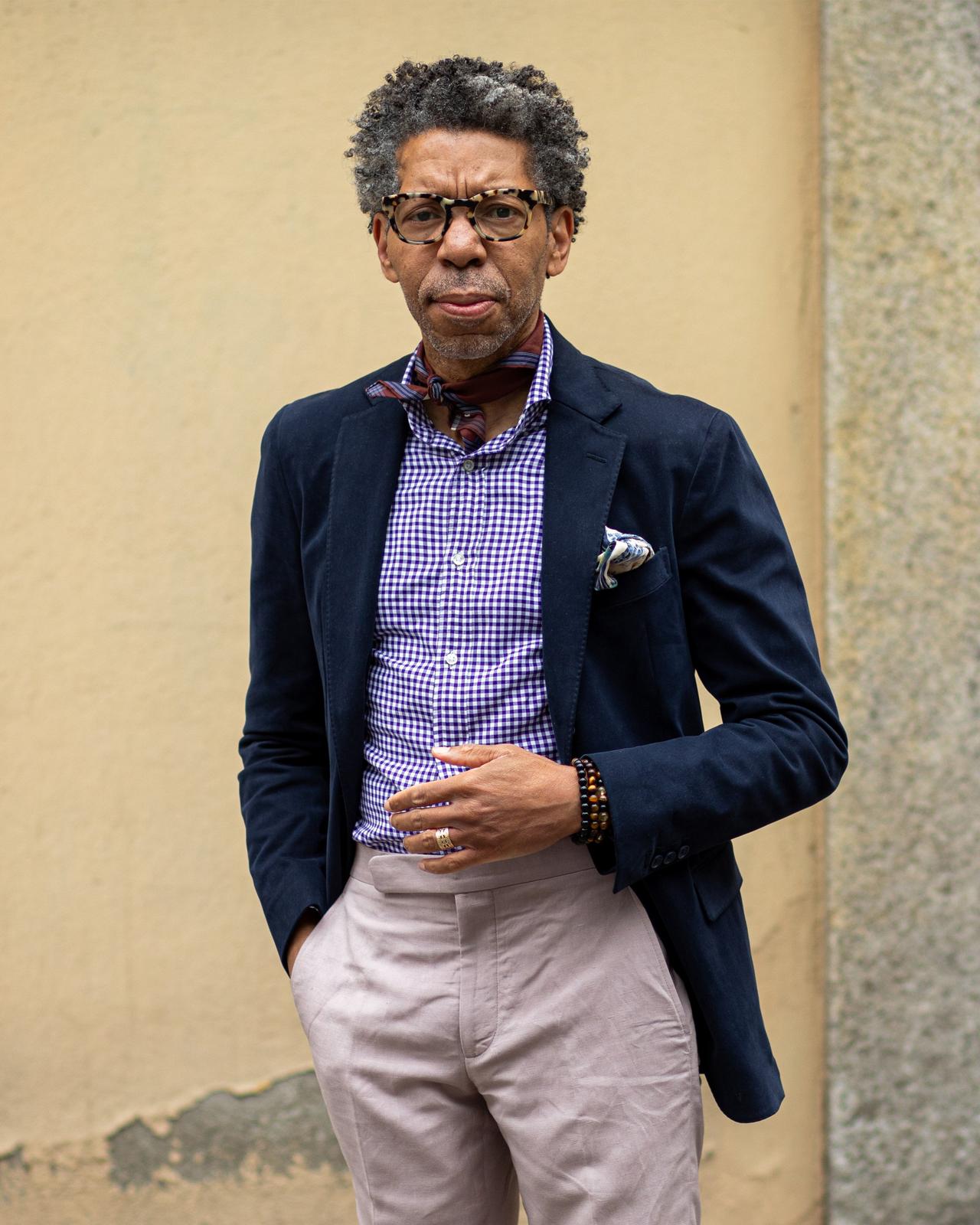 male in glasses wearing neck scarf, dress shirt, sport jacket with pocket square, dress pants and bracelets