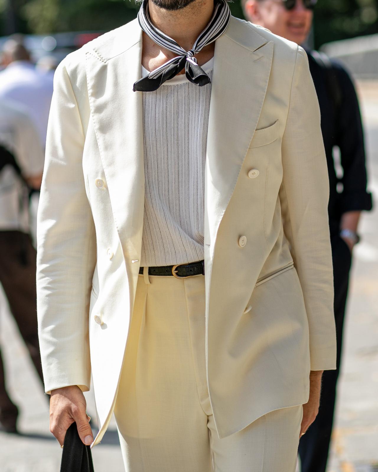 a man in a white suit walking down a street