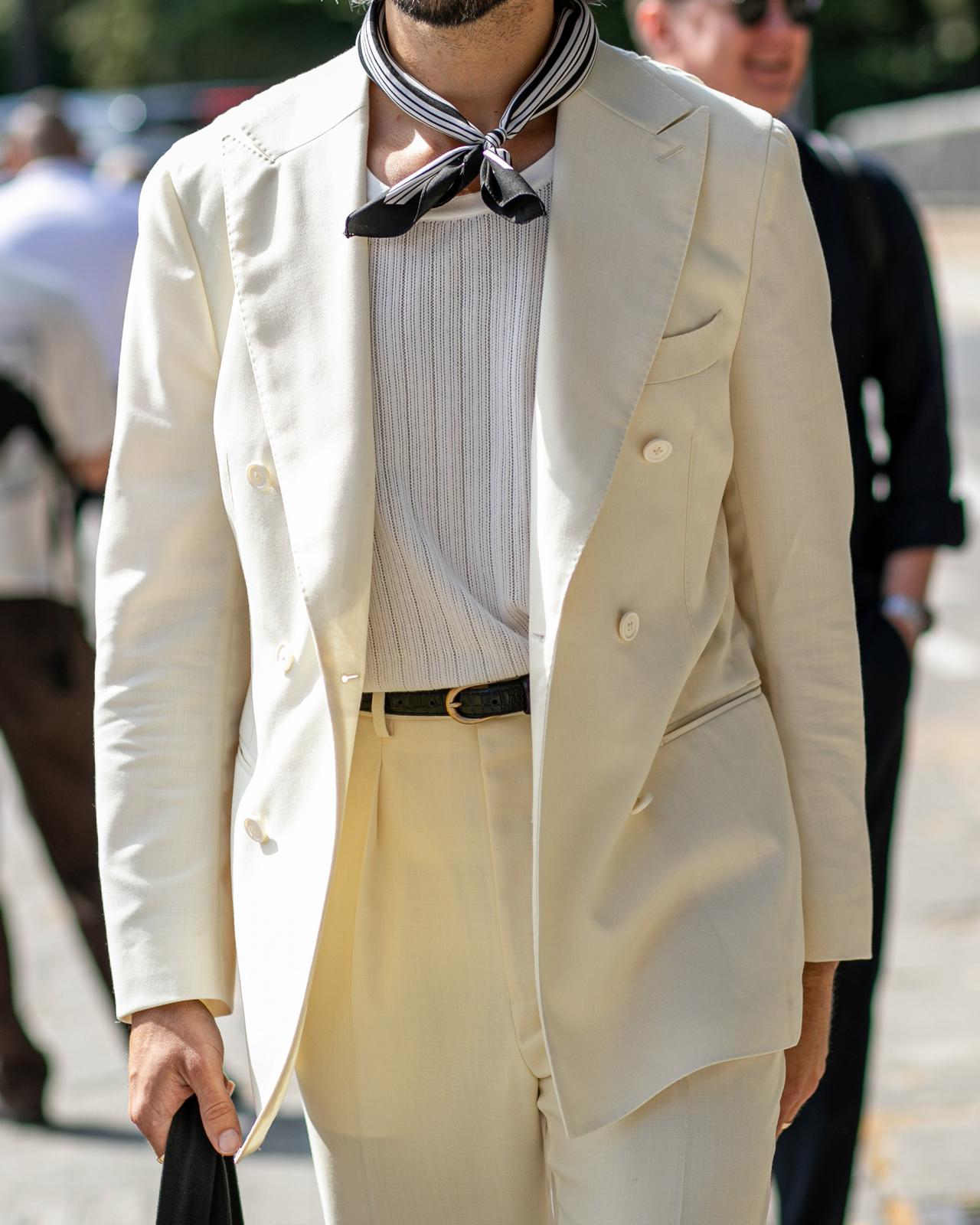 un homme en costume blanc marchant dans une rue