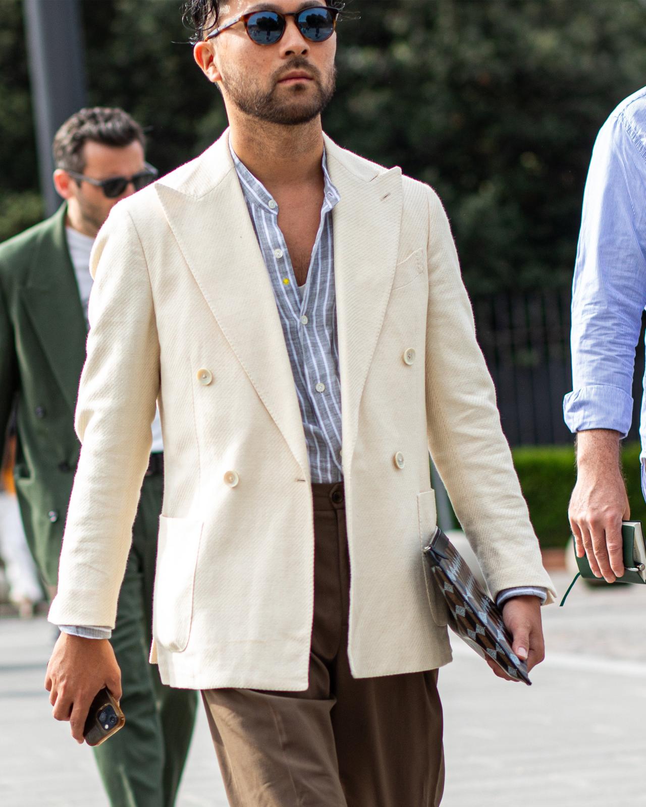 a man in a white suit walking down a street with other men