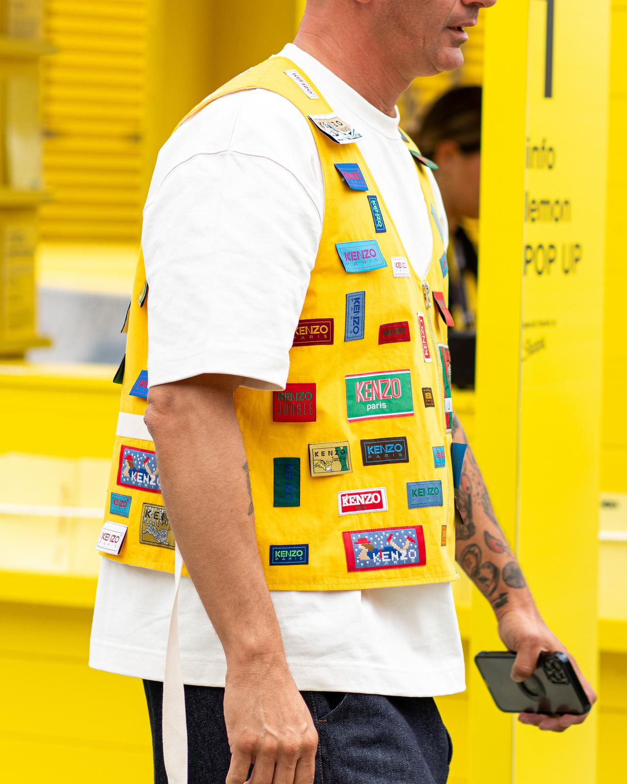 a man in a yellow vest with a cell phone in his hand