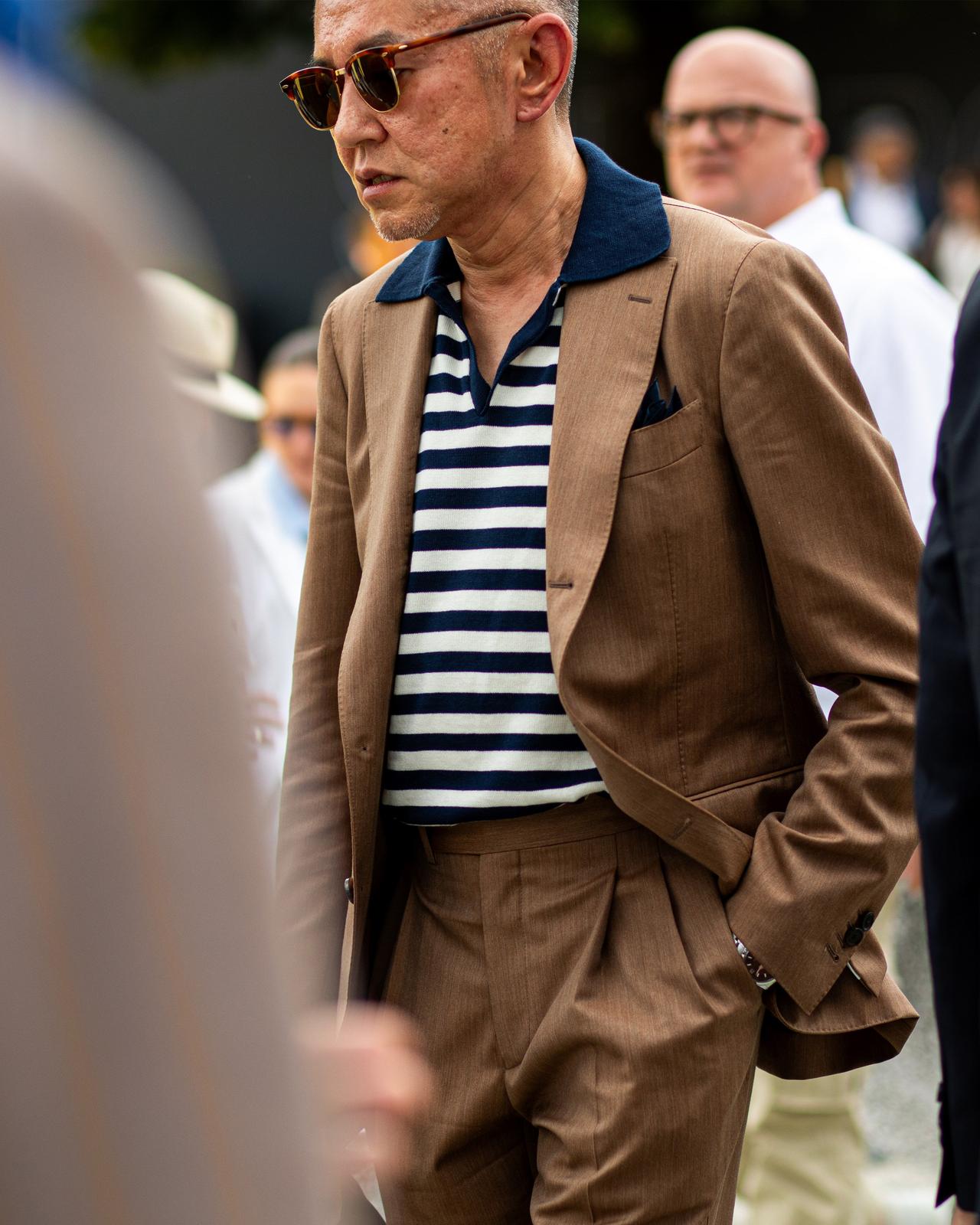 man wearing sport jacket and striped polo walking in the street
