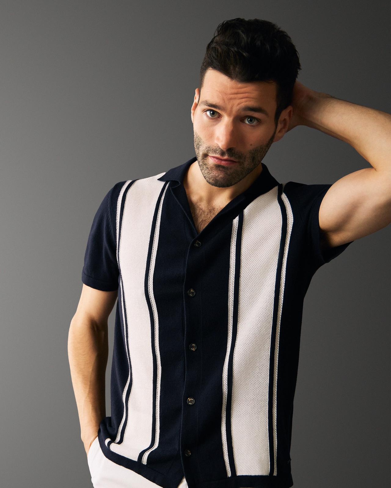 a man in a  striped knit polo with his arm up