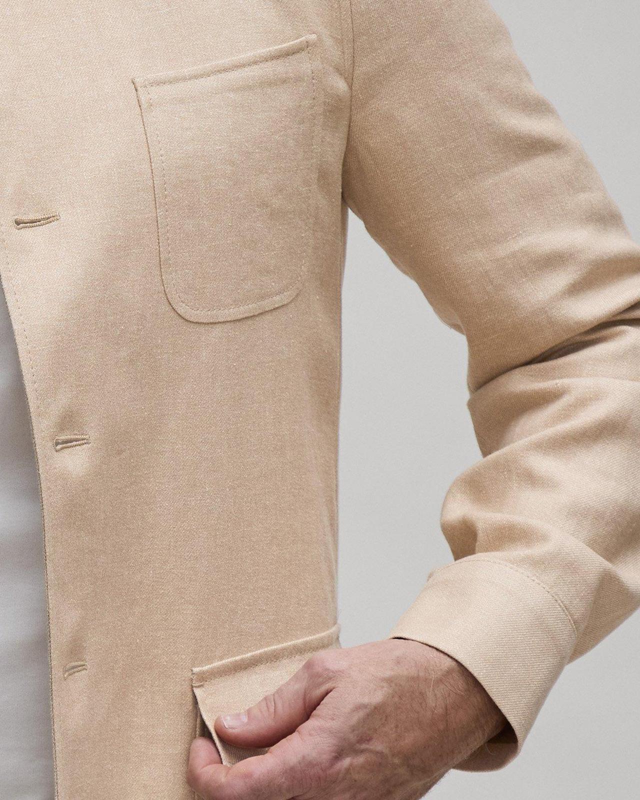 Un homme dans une veste beige avec sa main sur sa hanche
