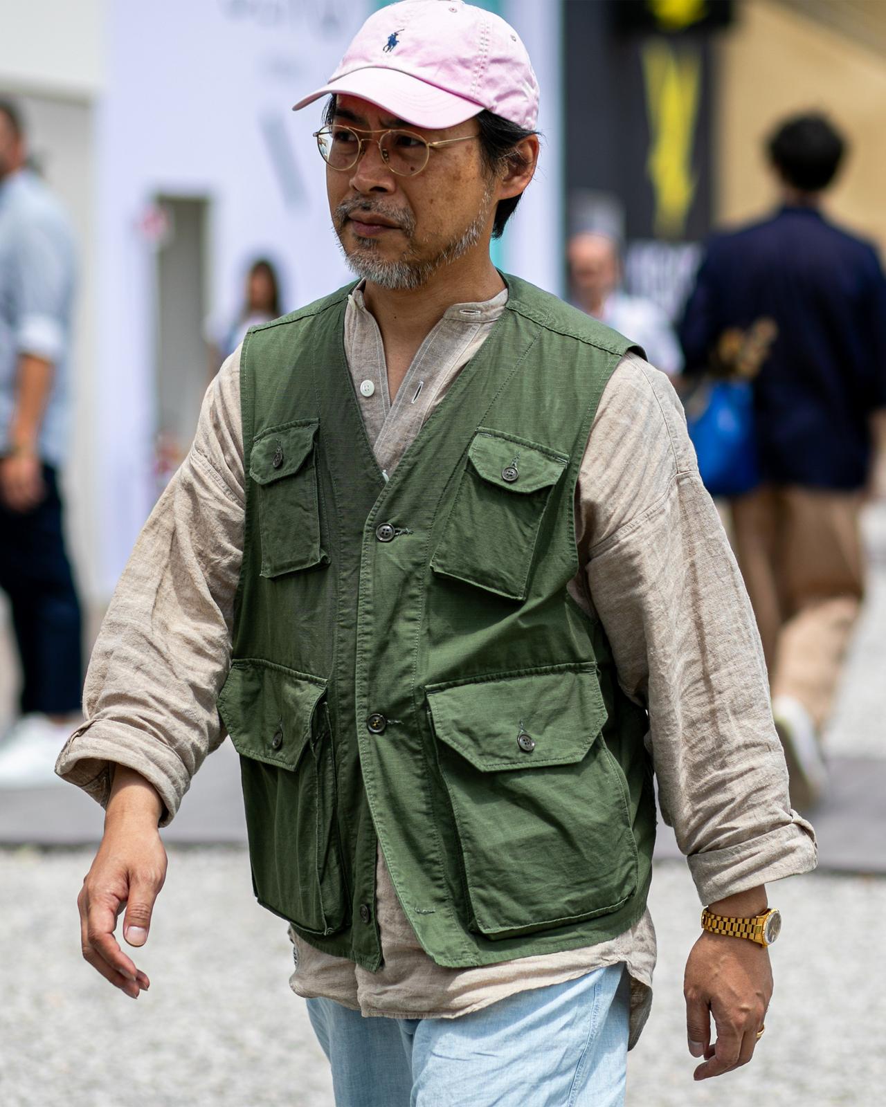 a man walking down a street with a pink hat on