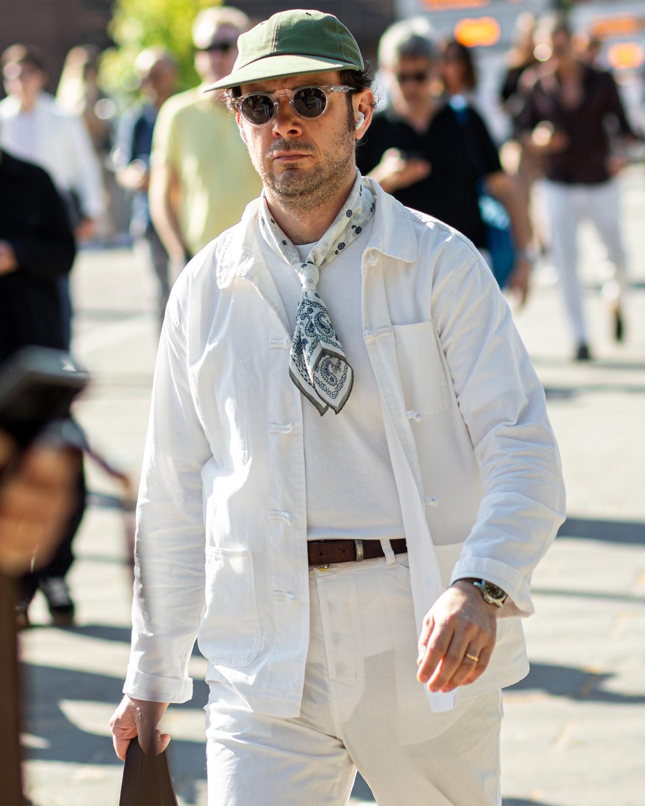 a man in white suit walking down a crowded street