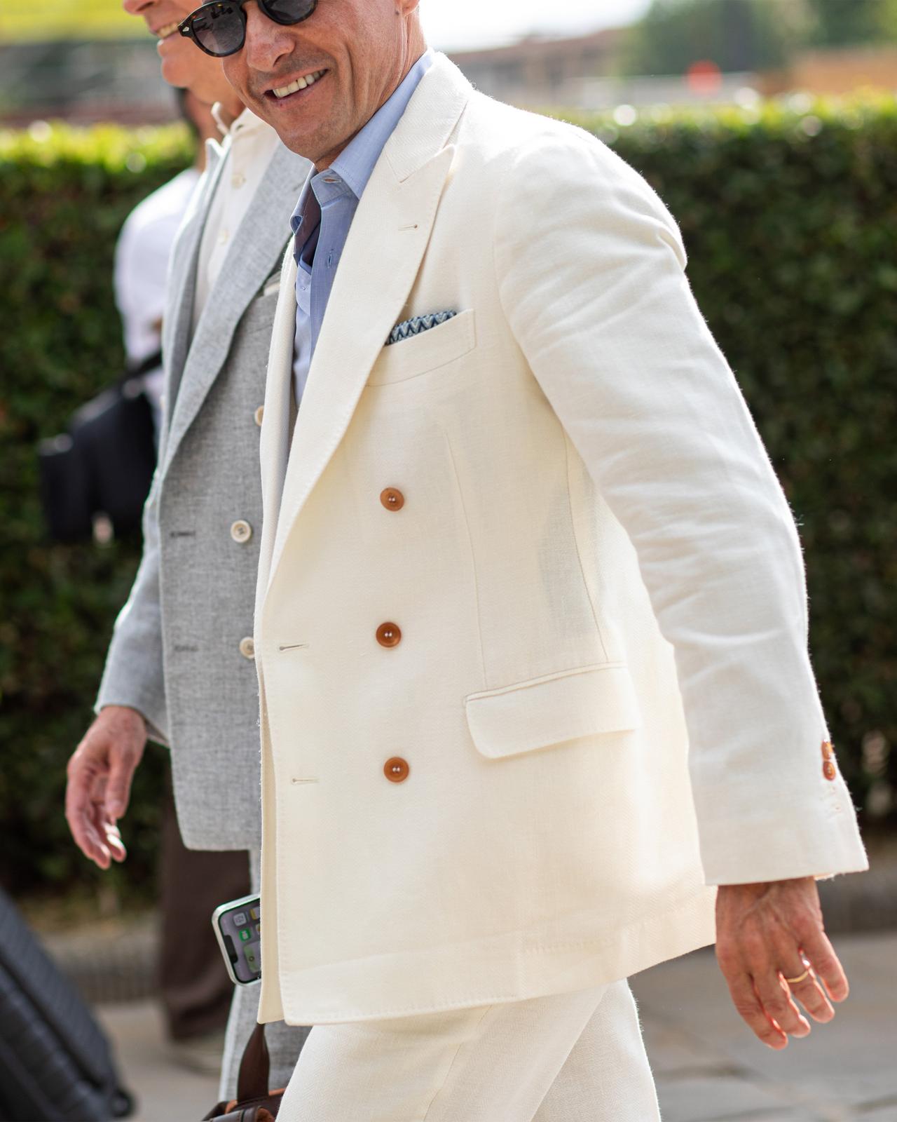 a man in a white suit walking down the street