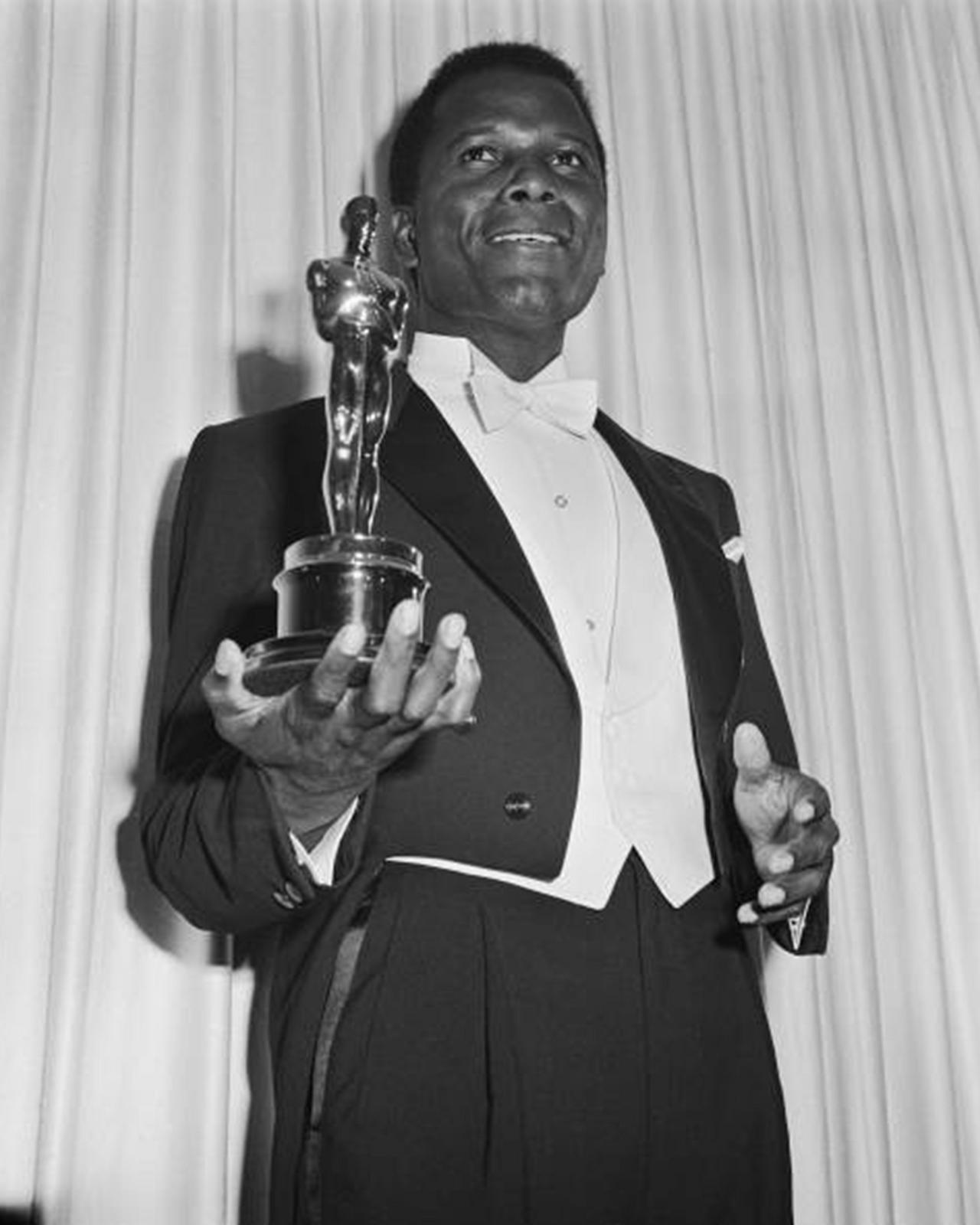 Sidney Poitier in a tuxedo holding an oscar statue