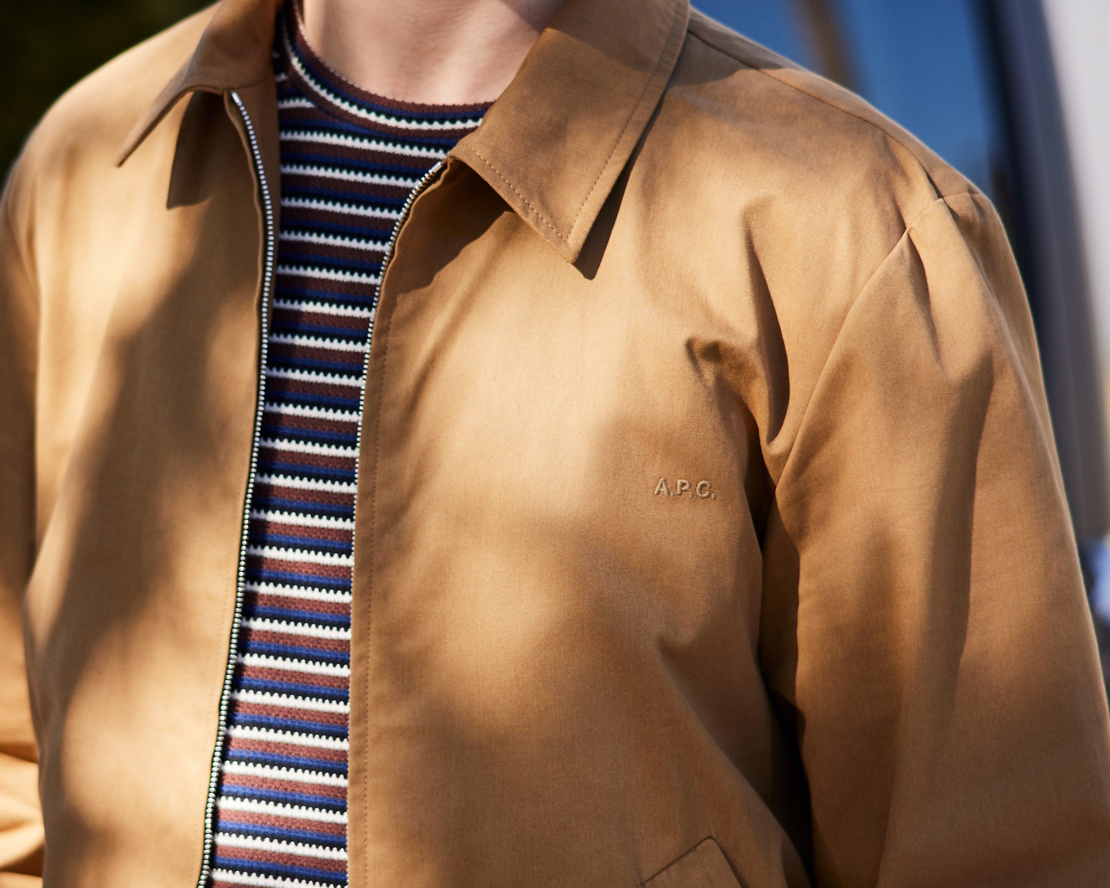 A man wearing a tan jacket and striped shirt