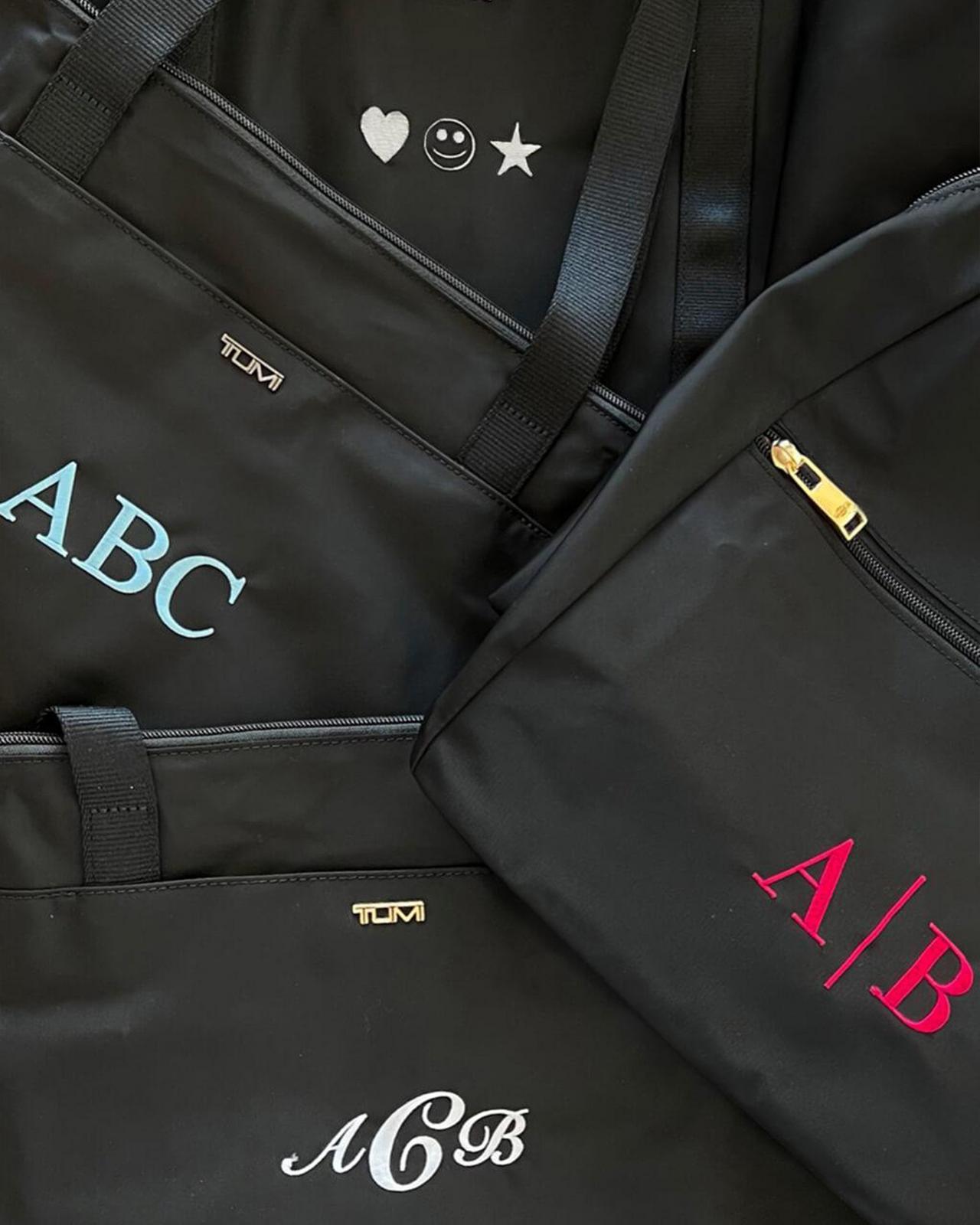a group of black bags with the initials of the people on them