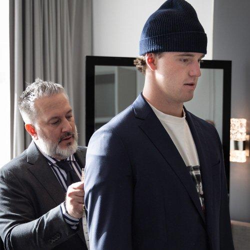 A man in a suit getting his jacket adjusted by another man