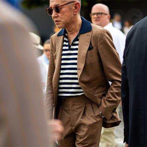 man wearing sunglasses, polo and sport jacket walking in the street