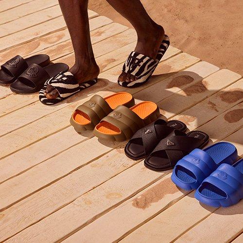 A person standing in front of a row of different colored sandals.