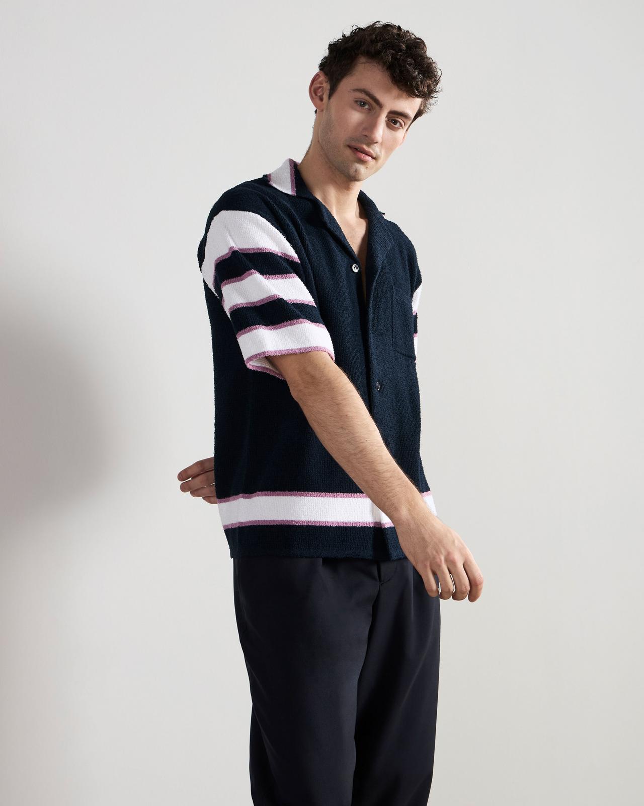 a man in a striped shirt and black pants standing