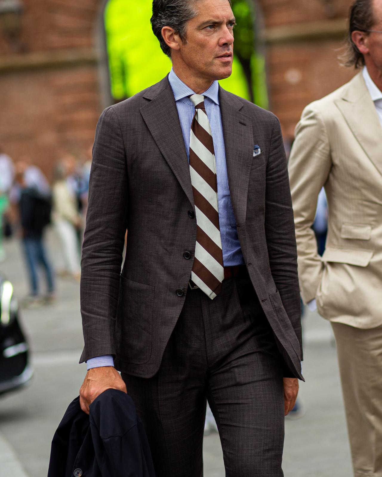 A man in a suit walking down a street with another man