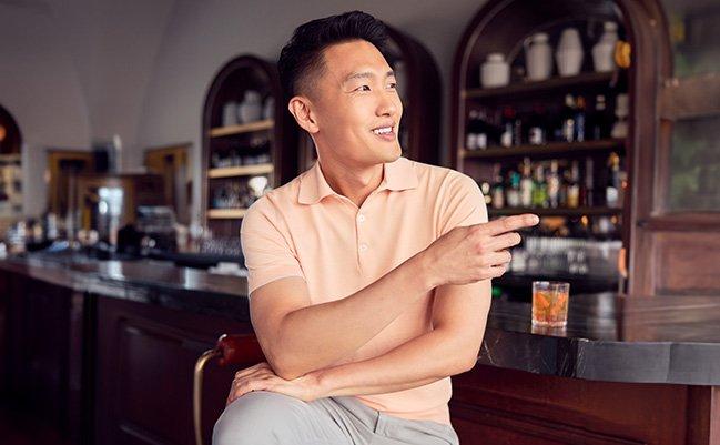 Male modelwearing navy Agnona polo with a coffee cup in hand