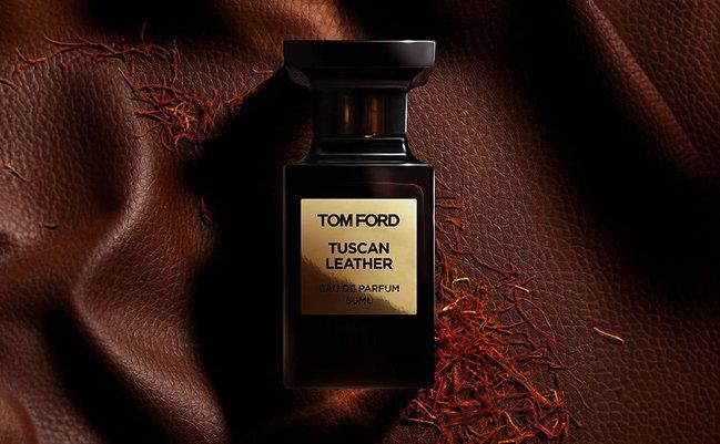 A bottle of Tom Ford Tuscan Leather perfume placed on a brown textured fabric